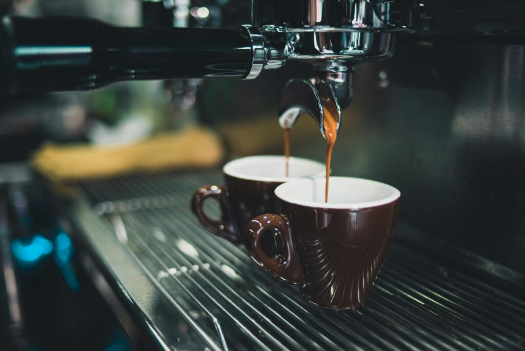 Fresh espresso coffee pouring into two brown cups from a coffee machine in a café setting